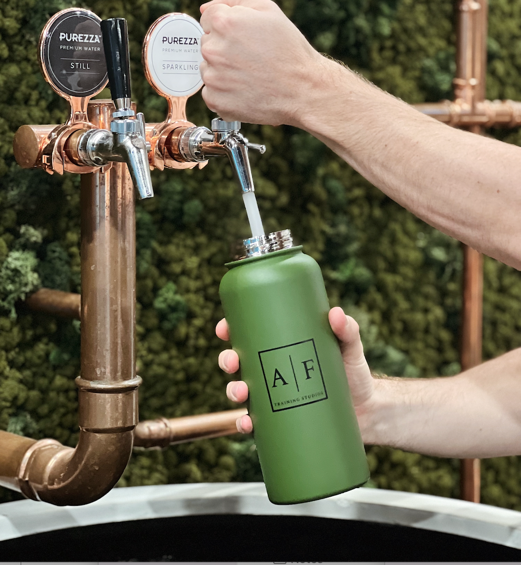 green stainless steel custom branded water bottle being filled with water under a water station