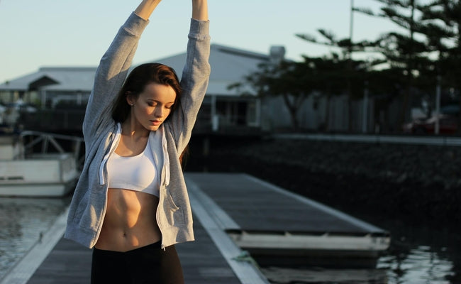 lady stretching outdoors in gym clothes on a pier